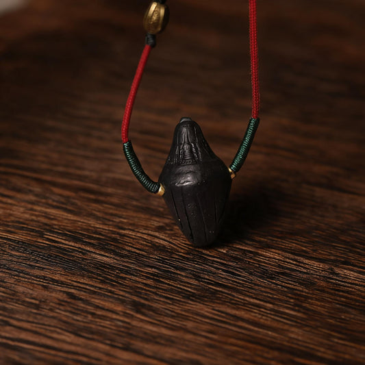 Close-up of black Nyangla clay pendant texture and carved lines