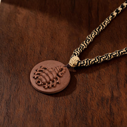 Scorpion round brown clay tsatsa pendant necklace flat lay