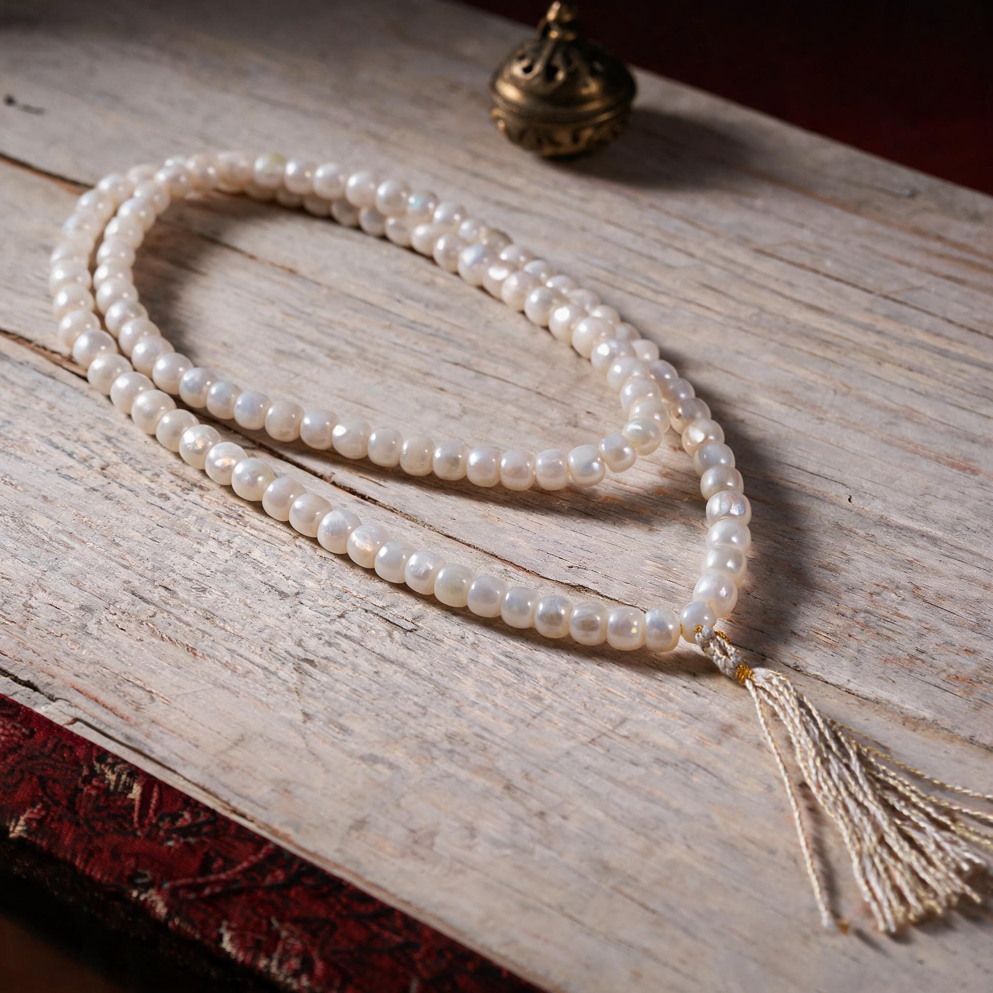 Handcrafted Mother-of-Pearl 108 & 27-Bead Mala Collection - Light of the Snowlands · 8×7 mm · 108 Beads · White-Gold Tassel - three-quarter view