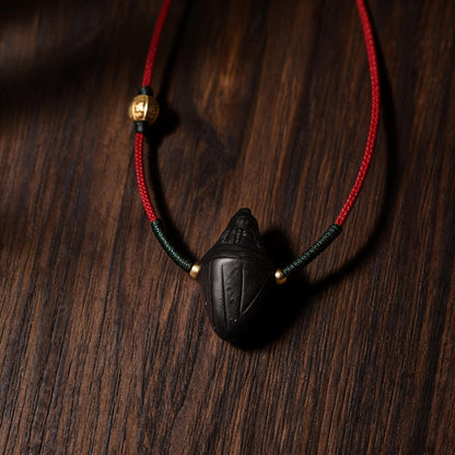 Close-up of red cord with green wrapping and brass beads