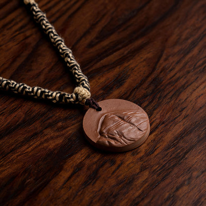 Angled side view of brown clay tsatsa pendant