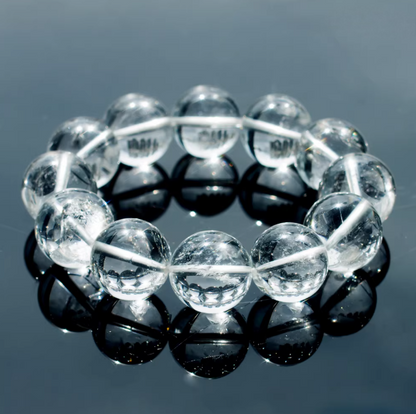 Clear quartz bead bracelet reflected on a dark surface