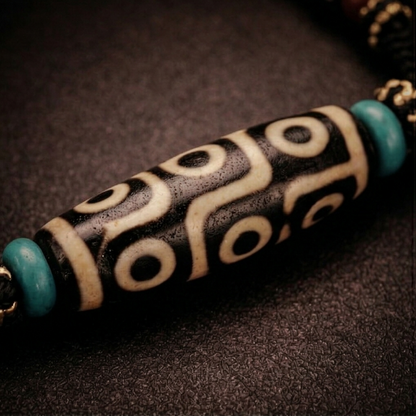 Close view of the nine-eye Dzi bead with turquoise accents